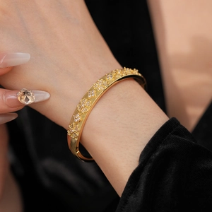 Detail of gold-plated flower bracelet featuring cubic zirconia and textured striped band