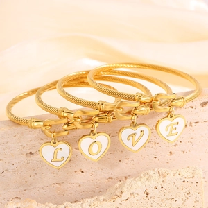 Golden woven bangles set with heart pendants featuring LOVE letters on marble background
