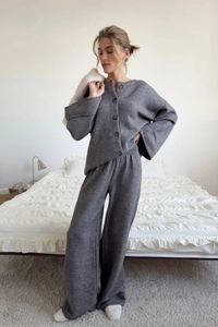 Detail of grey knitted cardigan and wide-leg trousers set in a cozy home setting