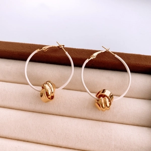 Detail showing the 18K gold plated knotted pendant and white circular ring earring design