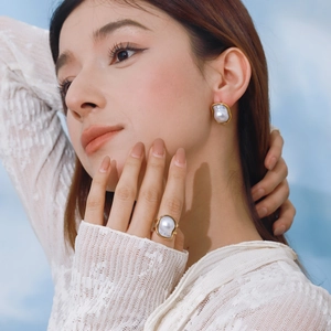 Close-up of model wearing baroque pearl jewelry set with gold ring and earrings