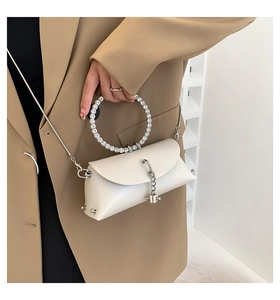 White handbag with rhinestone ring handle and silver chain strap worn with a blazer