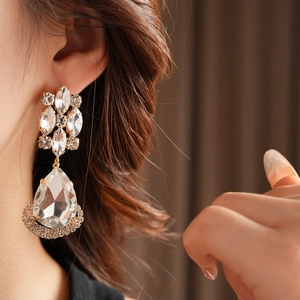 Close-up of vintage gold rhinestone diamond drop earrings worn on a female model