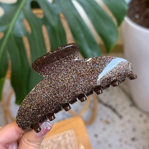 Detail of large colorful glitter hair claw clip with seven teeth on resin acrylic material