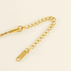 Macro view of 2mm gold twisted chain anklet detail with S.STEEL engraved tag