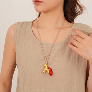 Golden horse pendant necklace with red tassel tail on wax cord worn by model