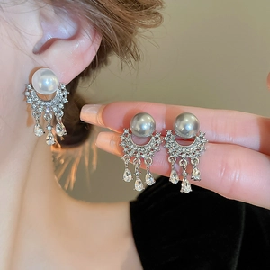 Detail of luxury pearl drop earrings with sparkling tassels and silver needles