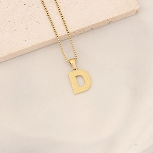 Detailed close-up of golden letter D pendant with textured surface on a box chain