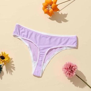 Flat lay of purple ribbed thong with white trim and decorative flowers on beige base