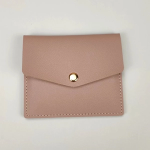 Detailed view of pink lychee textured leather mini card holder with gold snap and stitching