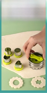 Macro view of stainless steel cookie mold with green handle cutting dough shapes
