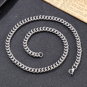 Close-up of a silver titanium steel Cuban link chain necklace on a black textured background