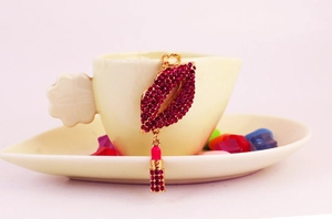 Detail shot of sparkling red rhinestone lipstick and lips keychain on a ceramic cup