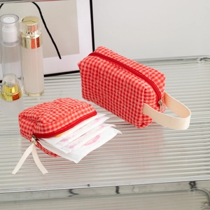 Close-up of red and white checkered quilted toiletry bags on a glass shelf