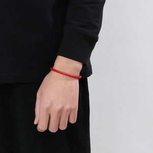 Gros plan d'un bracelet en cuir tressé rouge avec fermoir magnétique sur un poignet homme