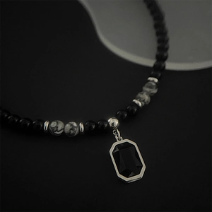 Close-up of black and white stone bead necklace with a faceted black rectangular pendant