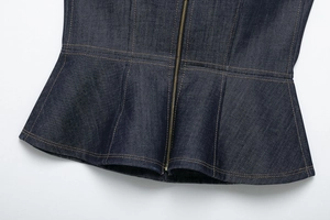 Detail of dark blue denim peplum top hem with zipper closure and contrast stitching