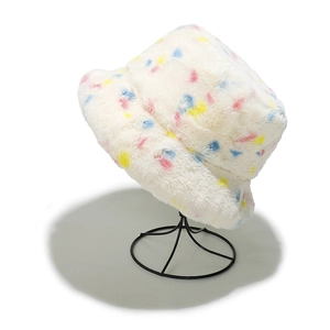 Detail of white faux fur bucket hat with colorful dots on a black metal display stand