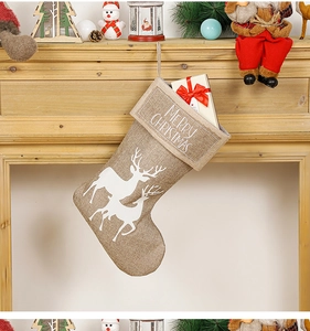 Close-up of burlap Christmas stocking with reindeer print hanging on a rustic fireplace