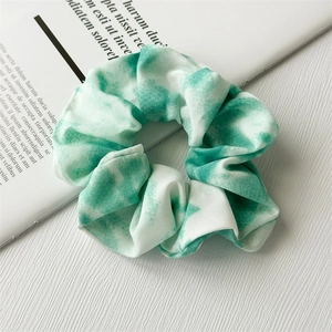 Detailed texture of white chiffon scrunchie with soft green tie-dye patterns and fabric pleats