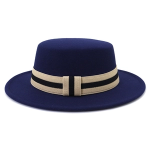 Detail of navy blue wool boater hat with a striped beige and black ribbon band