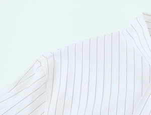 Detail of shoulder seam and fine brown stripes on a crisp white shirt fabric