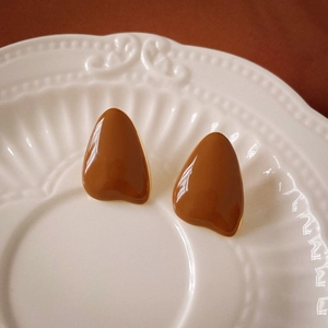 Detail of vintage caramel brown teardrop earrings on a retro embossed ceramic plate