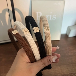 Detail of four knitted headbands in brown, cream, black and khaki with cute bunny patches