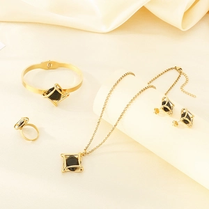 Luxe gold stainless steel jewelry set with black geometric stones on beige silk cloth