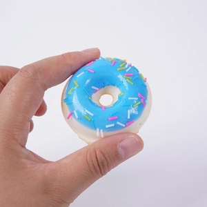 Realistic mini blue PU donut toy with colorful sprinkles held in hand on white background