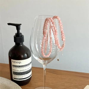 Detail of pink natural stone beaded necklace hanging on glass with silver heart pendant