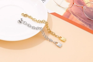 Macro detail of gold and silver chain bracelets with starburst padlock pendants