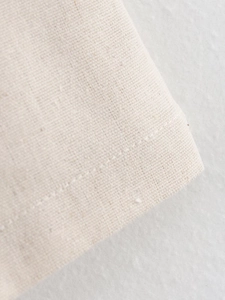 Close-up of beige linen fabric texture and precise stitching on the summer suit set