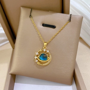 Dettaglio della collana d'oro con pendente pianeta blu in una scatola per gioielli