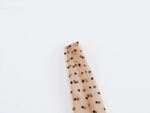 Dettaglio ravvicinato di tessuto a rete beige a pois neri su un abito elegante