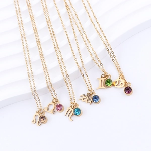 Detail of gold constellation necklaces with colorful birthstones on a white wave stand