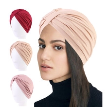 Multiple colors of twisted turban hats shown on mannequin heads and a female model