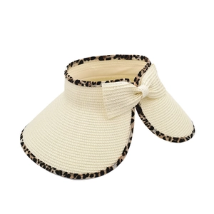 Close-up of leopard print edge and delicate straw bow on beige sun visor hat