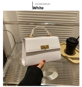 Detail of white crocodile texture handbag with gold metal lock and woven strap
