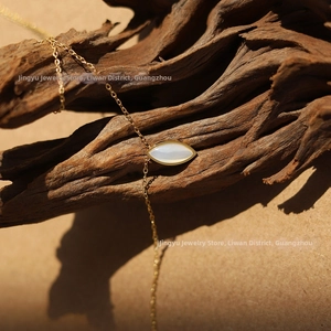 Close-up of gold marquise-shaped mother of pearl pendant necklace on a wooden branch