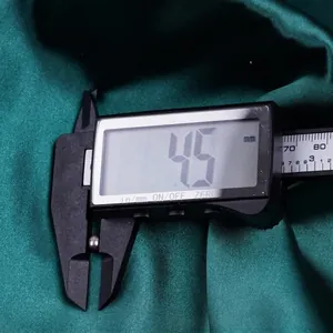 Freshwater rice pearl measured with a digital caliper showing 4.5mm diameter on silk fabric
