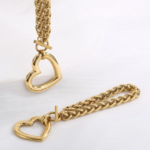 Detailed view of two chunky gold-tone braided chains with hollow heart pendants