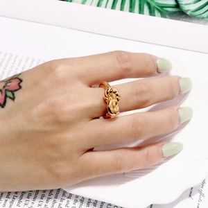 Nahaufnahme eines minimalistischen goldenen Knotensrings am Finger mit Politur-Finish