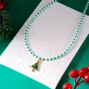 Detailed shot of beaded Christmas tree necklace on a decorative pine branch background