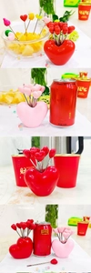 Macro detail of heart-shaped stainless steel fruit forks with ceramic storage base