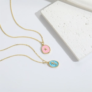 Detail of gold butterfly pendant necklaces with pink and blue enamel charms on stone