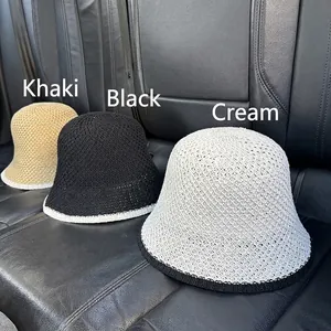 Three knitted sun hats in khaki, black and off-white with contrast trim on a car seat