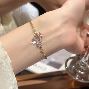 Close-up of gold flower bracelet featuring pink gems and sparkling crystals on model wrist