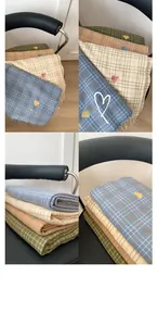 Detail of plaid scarves showing embroidered hearts and woven texture on a black chair