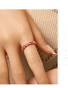 Detailed close-up of a gold band ring with ruby and diamond inlays on a finger